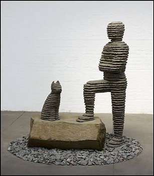 Boaz Vaadia Yizhaq with Cat (#106) (2009), bronze, basalt, and bluestone sculpture, 68 x 77 x 57 inches. A layered stone sculpture of a human figure with a cat, symbolizing companionship, natureâ€™s influence on art, and the balance of form and materialit