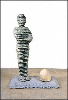Boaz Vaadia Zur (#3) (1993), bronze and bluestone sculpture, 49 x 35 x 19 inches. A layered stone figure stands with arms crossed, accompanied by a natural boulder on a rectangular stone base, illustrating Vaadiaâ€™s signature sculptural technique blending